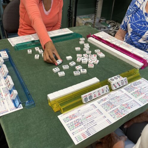 four players at a mah jongg table, players are not fully shown